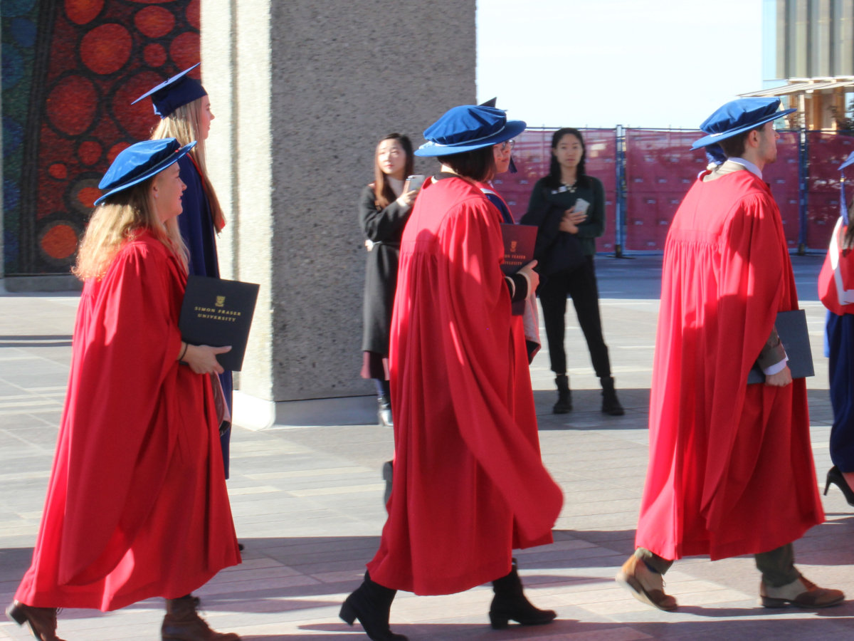 Doctor Hag walks carrying her doctorate at graduation.