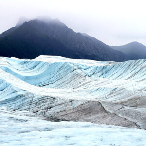 Glacial carved misty valley filled with waves of blue ice.