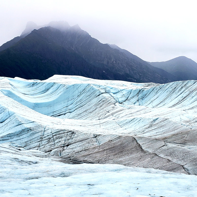 Glacial carved misty valley filled with waves of blue ice.