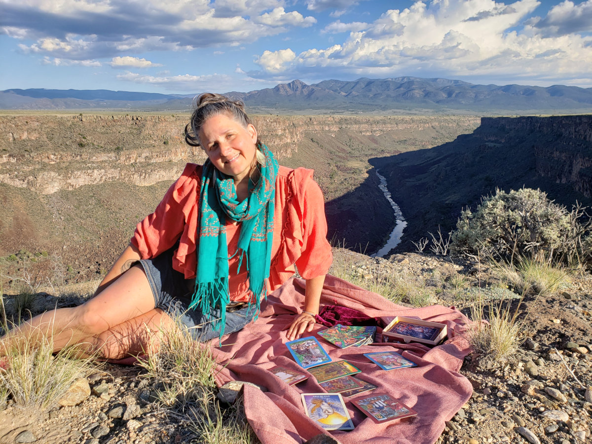 A smiling hag reads tarot cards next to the Rio Grande rift.